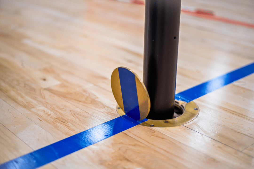 Volleyball floorplate installed in gym hardwood floor for safe net setup