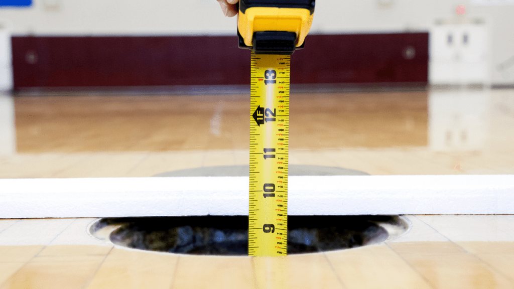 volleyball floor sleeve being measured for depth